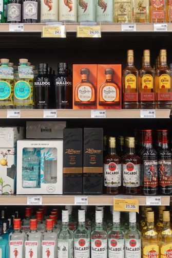 Athens, Greece - March 6, 2023: Tequila gin and rum alcohol beverage bottles various labels for sale at liquor store.