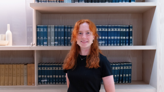 Student Hannah Pola stands in front of shelves of law volumes