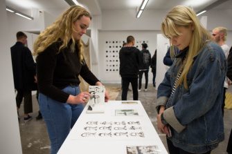 Two blonde girls browse the Honours Art and Design Gallery
