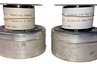 A photograph of two microfilm rolls which contain books. One is Hopalong Cassidy by Clarence C Mulford, and the other is Windows for the Crown Prince by Elizabeth Gray Vining. The microfilm rolls are labelled, and sit atop circular storage tins.