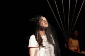 Female student on stage with eyes closed looking up