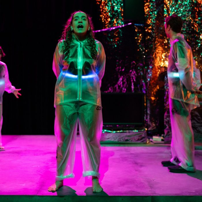 three students acting on stage