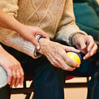 Close up of an elderly person's hands holding a stress ball