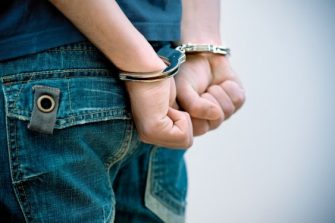 Person whose hands are handcuffed behind back