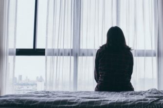 Woman sitting alone in room looking at window