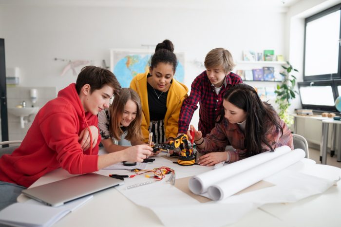 A group of students building and programming electric toys and robots at robotics classroom