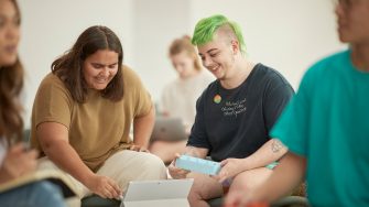Art and design students discussing work inside the Red Center build enviroment study space.