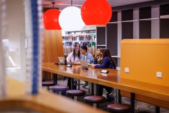 Four students talking at a library table