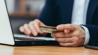 Close-up photo of businessman making online shopping in online store, man using laptop, man holding credit bank card