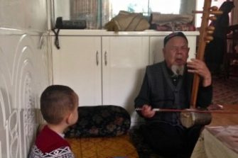 Ömär-Qari's grandson listens to his grandfather sing at home, 2014