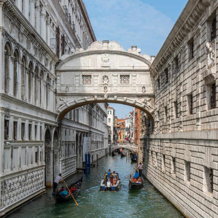 People touring in gondolas under the famous baroque style Bridge of Sighs at Venice city, Italy.