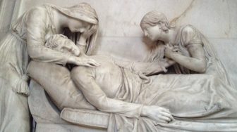 A statue of two women crying over the laying body of a man