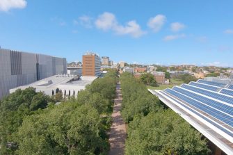 Campus mall walkway aerial shot showing solar panels and green trees lining the main mall