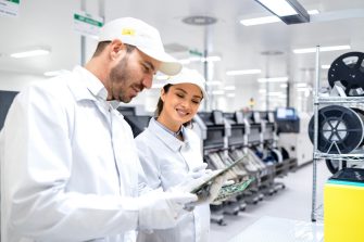 Experienced quality control workers checking electronics components in production factory.