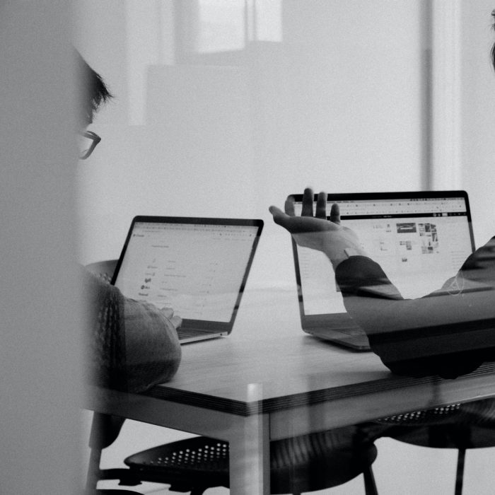 Black and white photo of two people working on laptops