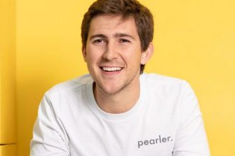 Kurt Walkom smiles in a pearler shirt against a yellow background