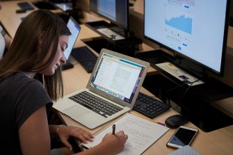 Business School Applied Economics student working on calculations at a computer