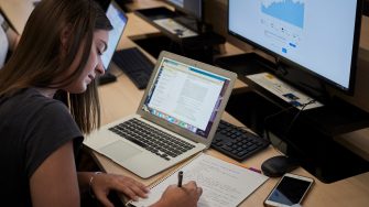 Business School Applied Economics student working on calculations at a computer