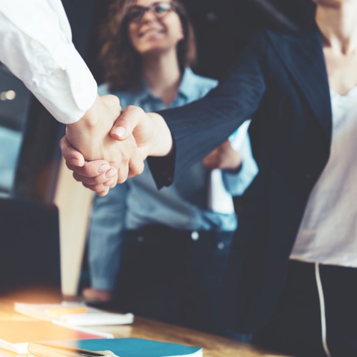 Young business people shaking hands in the office. Finishing successful meeting. Three persons