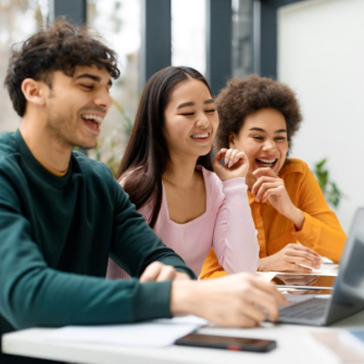 Students laughing around a laptop