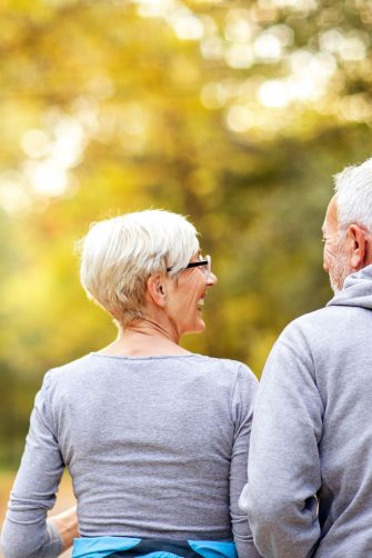 Grey haired male CEO executive manager mentor with beard giving consultation on financial operations to female African American colleague intern using laptop sitting in modern office near window.