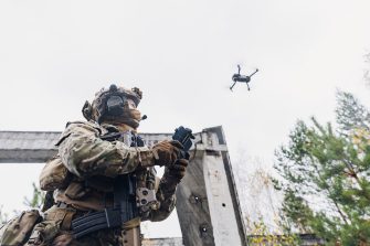 Military soldier controls drone for reconnaissance operation of enemy positions. Concept using quadrocopters in smart war.