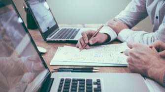 Close up of people working with laptops and papers