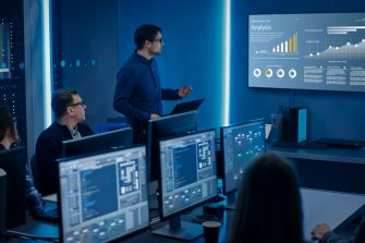Team of Professional IT Developers Have a Meeting, Speaker Shows Growth Data with Graphs, Charts, Software UI. Shown on TV. Concept: Software UI Development, Deep Learning, Graphs, Charts.