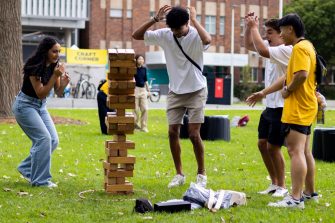 Students playing a game of giant Jenga at O-Week on the grass beside University Mall.