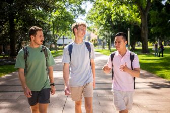 Three students chatting while walking on the Kensington Campus main walkway, University Mall
