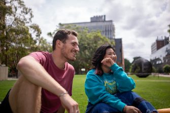 A group of students chatting while sitting on Globe Lawn on Kensington Campus