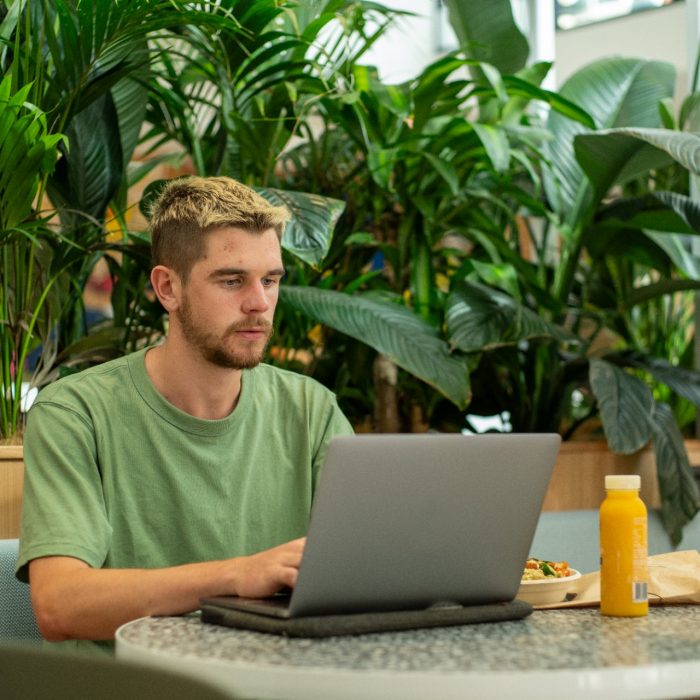 A student sitting at their laptop while eating lunch on Kensington Campus