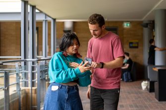 Students looking at their phones outdoors in the Quadrangle Building