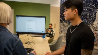 A student chatting to a staff member in the student hub on Paddington Campus