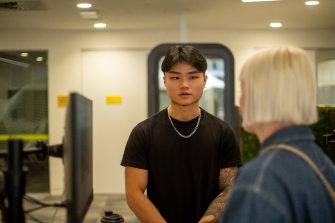 A student chatting to a staff member in the student hub on Paddington Campus