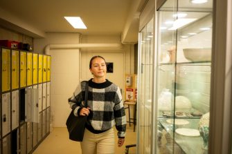 Students chatting while walking alongside glass cabinets on Paddington Campus