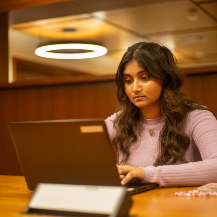 Students using their laptops at a shared desk in the library