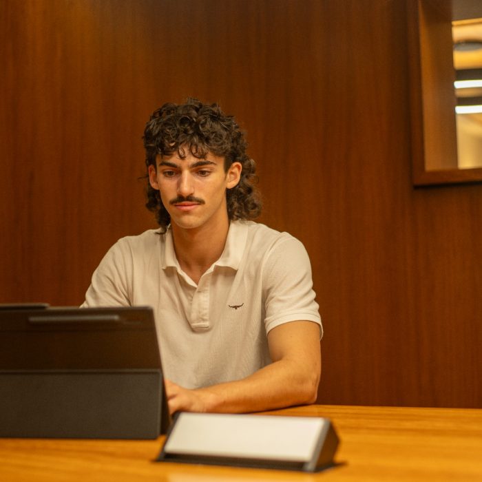Students using their laptops at a shared desk in the library