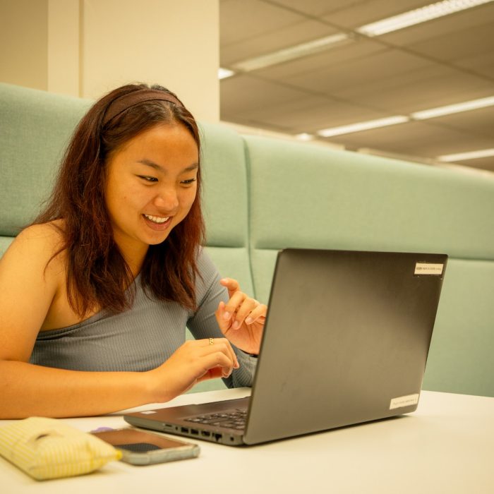 Students using their laptops at a shared desk in the library