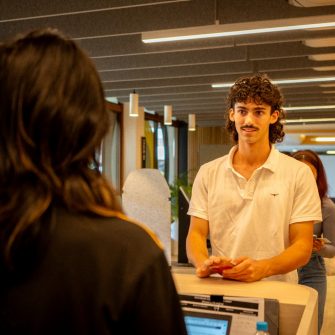 A student speaking to a staff  member at the concierge desk in The Nucleus: Student Hub