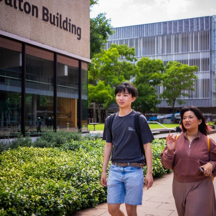 Two students chatting while walking through Kensington Campus