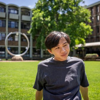 A student smiling while sitting on the grass on Library Lawn on Kensington Campus