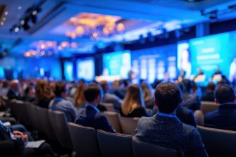 A crowd of people attends a business conference presentation in blue tones, showing corporate atmosphere and engagement Great for illustrating professional development topics.
