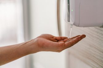 Woman hand using wash hand sanitizer gel dispenser automatic machine for prevent Coronavirus