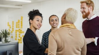 Colleagues standing in a small group discussing something while working at an office.