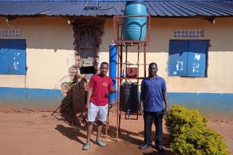 Two people standing beside the UV-C Water Treatment Unit.