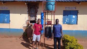 Two people standing beside the UV-C Water Treatment Unit.