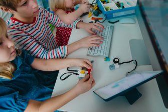 kids building robot and programming it with touch pad and computer, modern technology and STEM, online learning