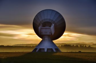 A satelite dish backlit in the sunrise