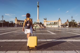 Young woman with suitcase just arriving in Budapest and walking through Heroâ  s square